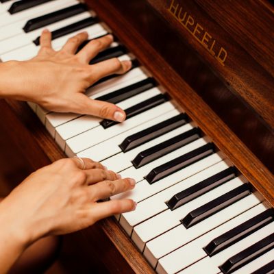 Musician's hands playing wooden piano keys in a high contrast image, capturing musical expression.